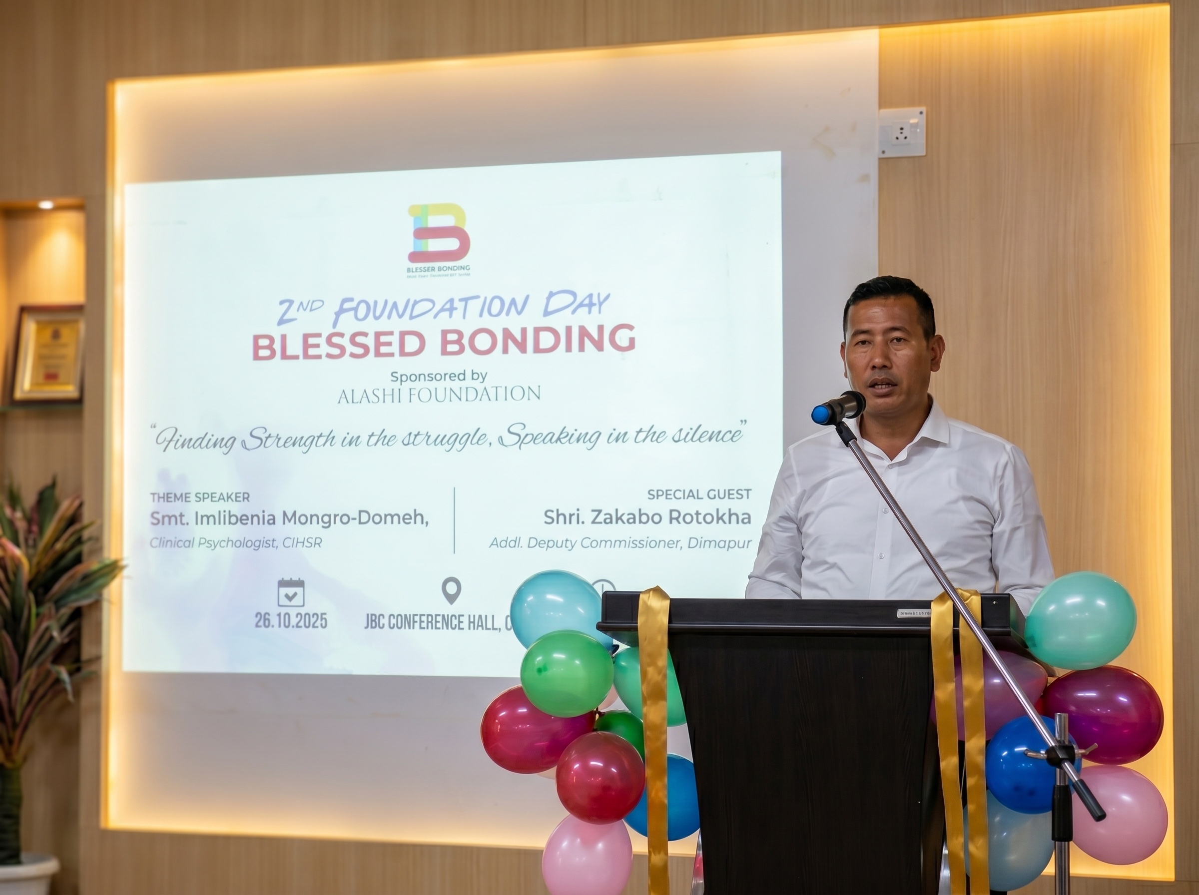 A speaker at the podium during the second Foundation Day, with the Blessed Bonding banner behind him