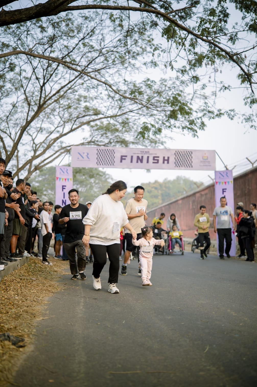 A mother and child walking toward the finish arch at a community walk